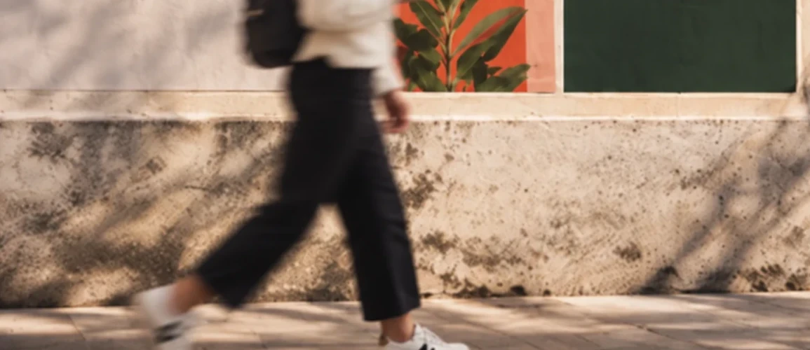 Detalle de unos pasos en movimiento frente a una pared con carteles